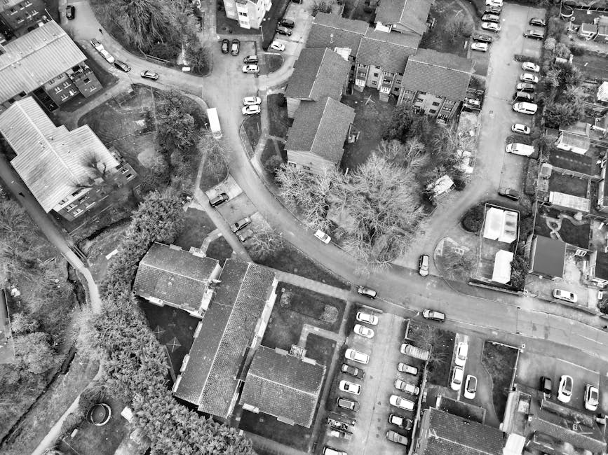 An aerial view of a residential neighbourhood featuring densely packed houses and streets, with some rooftops showing a light dusting of snow. The houses are primarily brick and timber constructions w