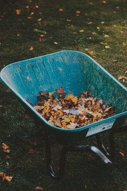 A large white plastic bucket positioned on a patch of grass outdoors, filled with various small to medium-sized wooden sticks and branches with rough, uneven textures and dark brown to blackish hues.